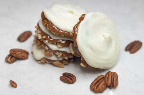 Stack of turtles with white icing and pecans on a light surface